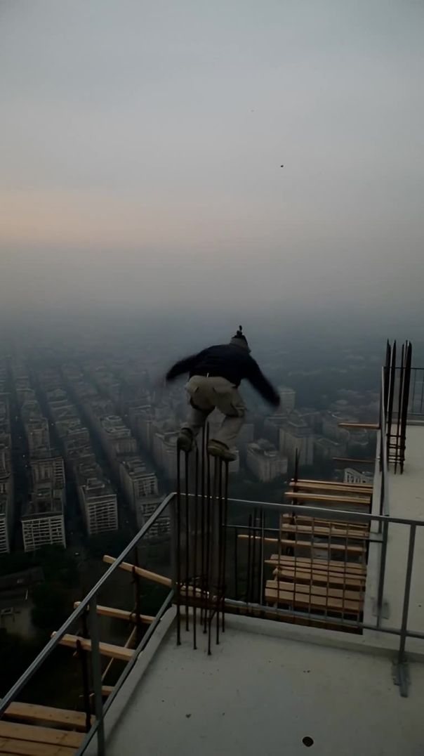A shaky first-person view of a person parkouring on a foggy skyscraper construction site
